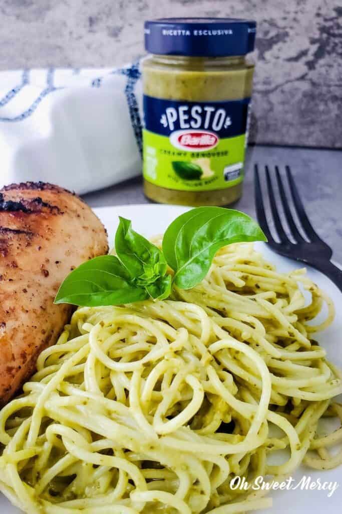 Photo of pasta and grilled chicken with jar of Barilla Creamy Genovese Pesto in background