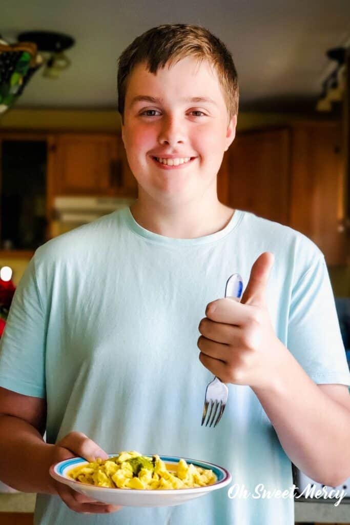 Big thumbs up from my son holding a plate of scrambled eggs with barilla pesto.