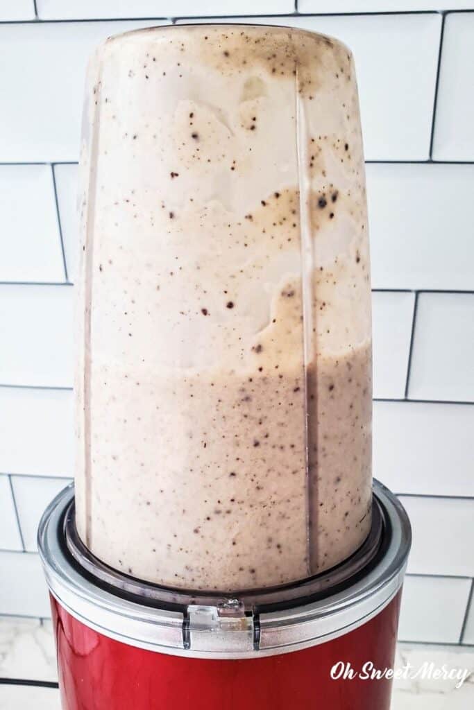 Bullet style blender with blended chocolate chip shake in it.