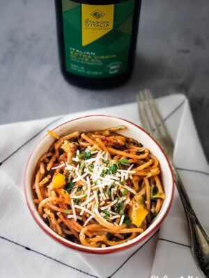 Bowl of Roasted Garlic and Vegetable Pasta with bottle of 100% Italian Extra Virgin Olive Oil in background