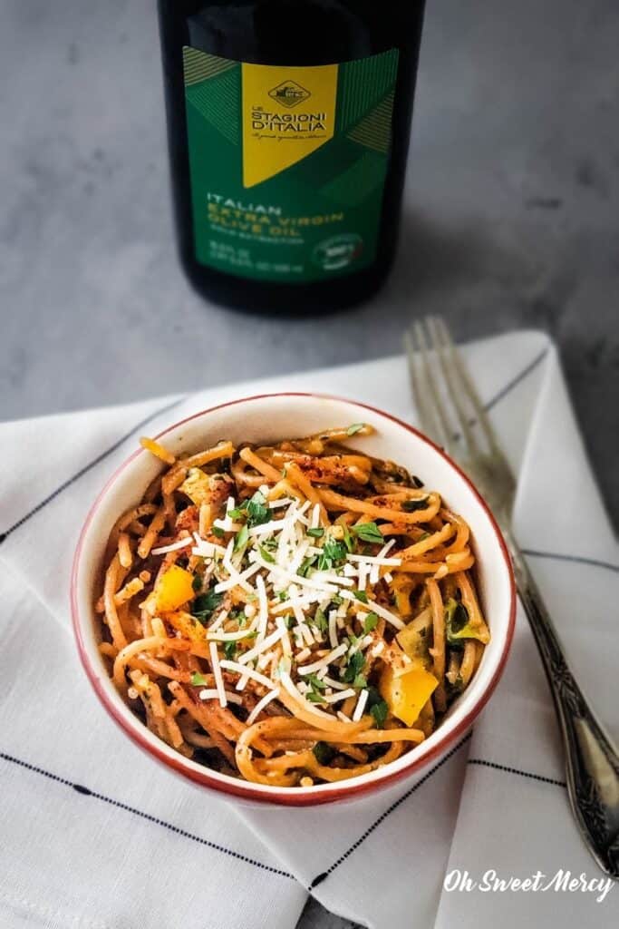 Bowl of Roasted Garlic and Vegetable Pasta with bottle of 100% Italian Extra Virgin Olive Oil in background