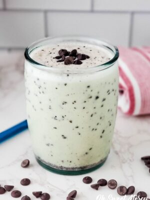 Glass of Dairy Free Chocolate Chip Shake, THM S. Blue straw and folded red striped towel in background.