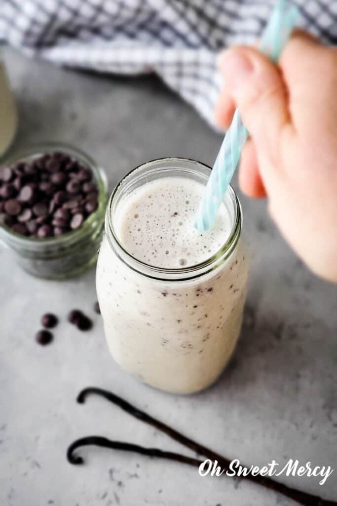 Putting a straw in a glass of chocolate chip shake.