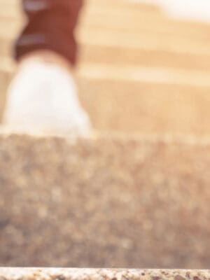 Person's feet stepping up a stair symbolizing growth and choosing a new path.
